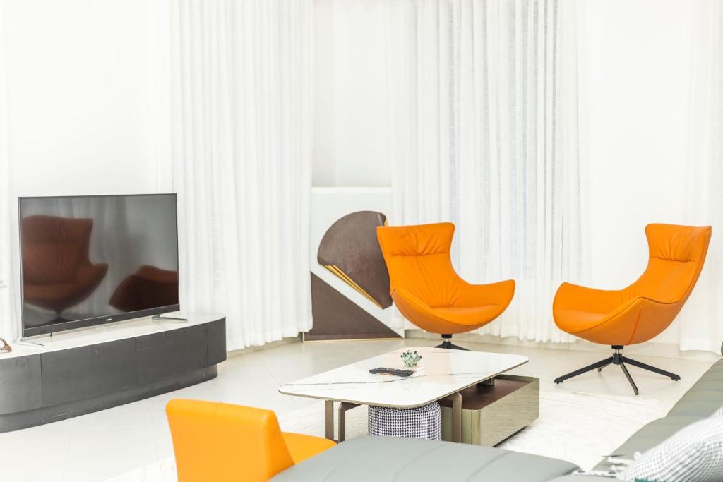 YomboBWAGAmoyo by Enamour的客厅配有橙色椅子和电视