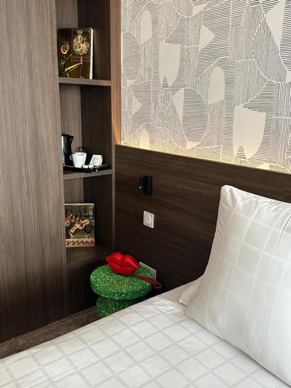 蒙托邦Dali Hôtel Montauban的一间卧室配有一张带枕头和绿色搁脚凳的床