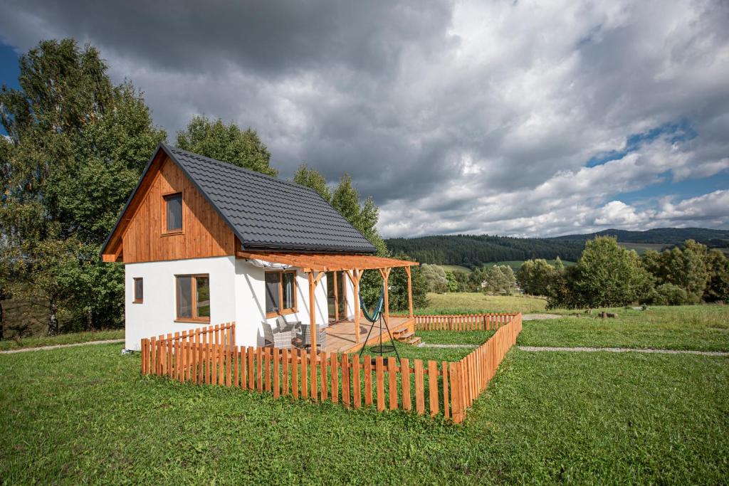 下乌斯奇基Pastelova Krova - domki w Bieszczadach的田野上带木栅栏的小房子