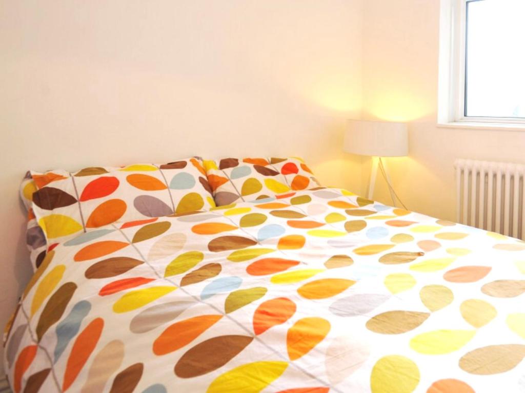 伦敦Waterloo Central London的卧室内一张带五颜六色棉被的床