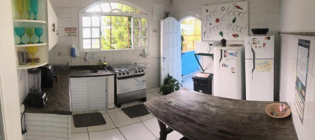维多利亚Onça da Praia Hostel的一间厨房,配有白色家电和木制长凳