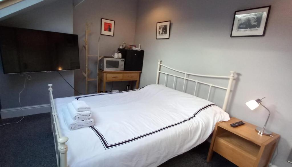 HillsboroughSerene Homes Sheffield, Private Ensuite Velux Room的卧室配有一张白色的床、电视和一张桌子