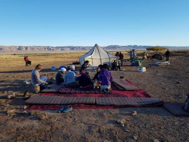 梅尔祖卡GITE Take Ur time的一群人坐在沙漠的帐篷周围