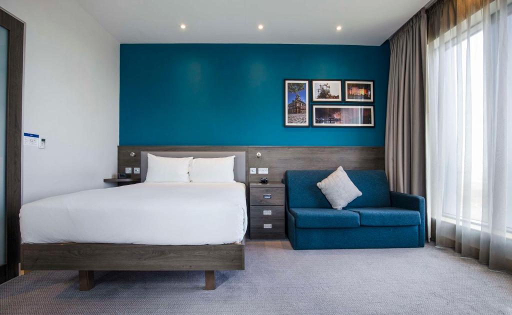 蒂斯河畔斯托克顿Hampton By Hilton Stockton On Tees的一间卧室配有一张床和一张蓝色椅子