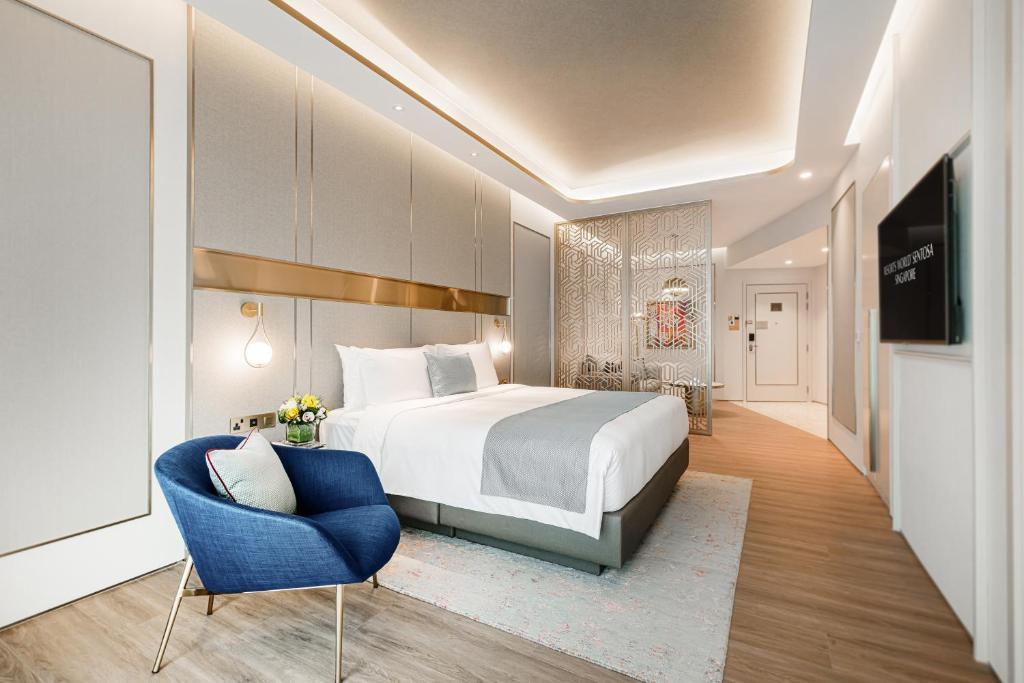 新加坡Resorts World Sentosa - Crockfords Tower的酒店客房,配有一张床和一张蓝色椅子