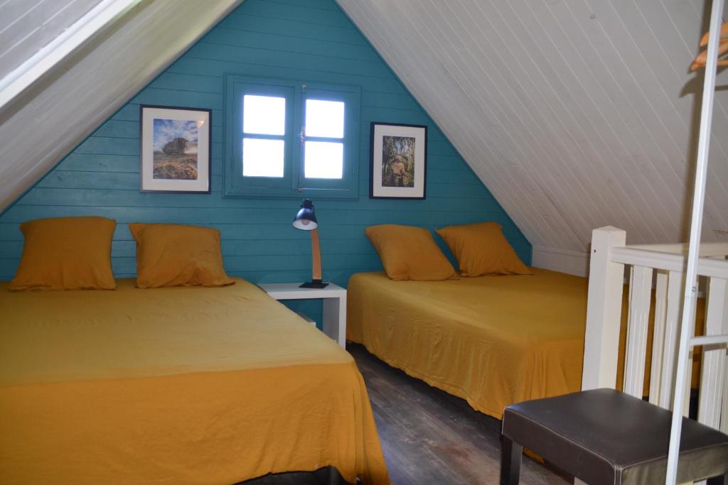 FleurimontLa Petite Kaz Dans la Savane的阁楼间设有两张床铺和蓝色的墙壁
