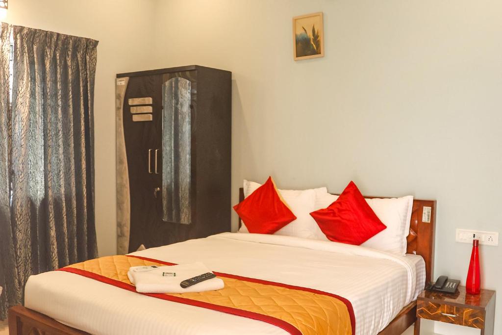 钦奈FabHotel Home Tree Service Apartment Kolathur的一间卧室配有红色枕头的床