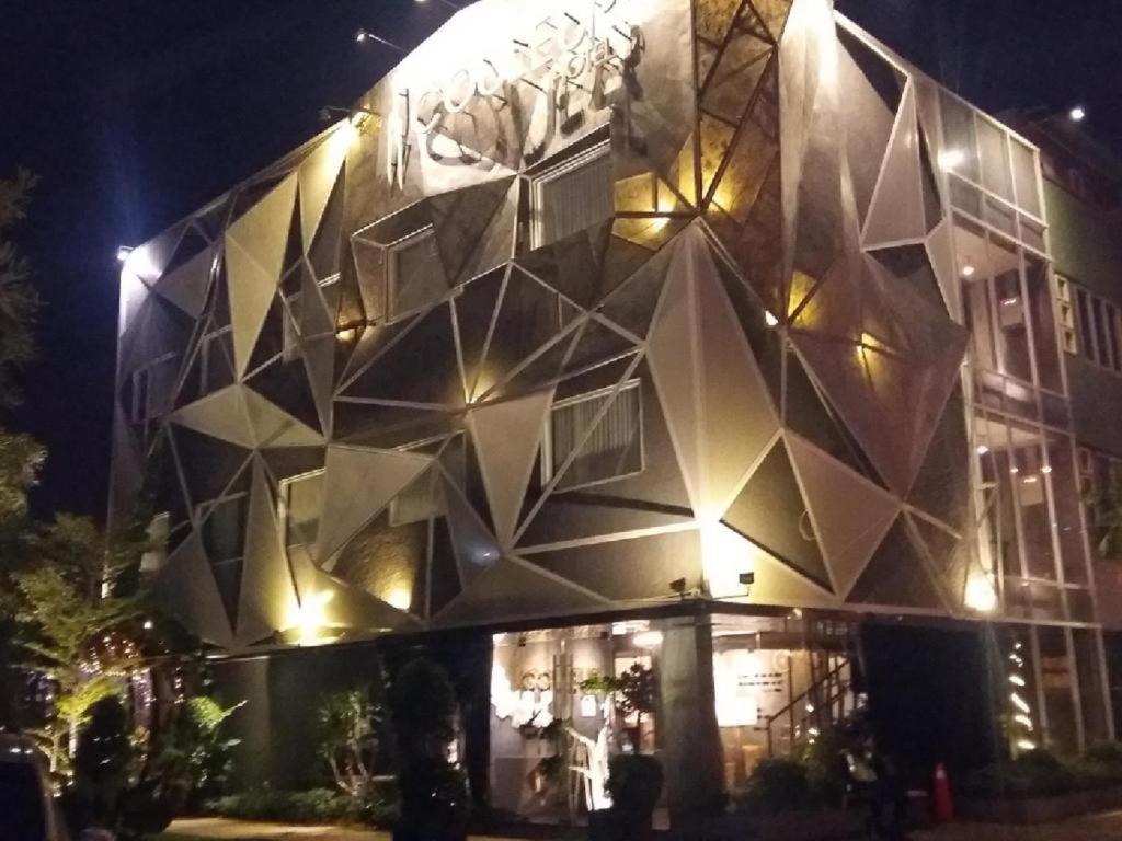 雅加达Couleur Hotel Cengkareng的一座在晚上有几何外墙的建筑
