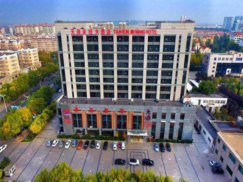 青岛Qingdao TianRun JinWang Hotel的一座大型建筑,前面设有停车场