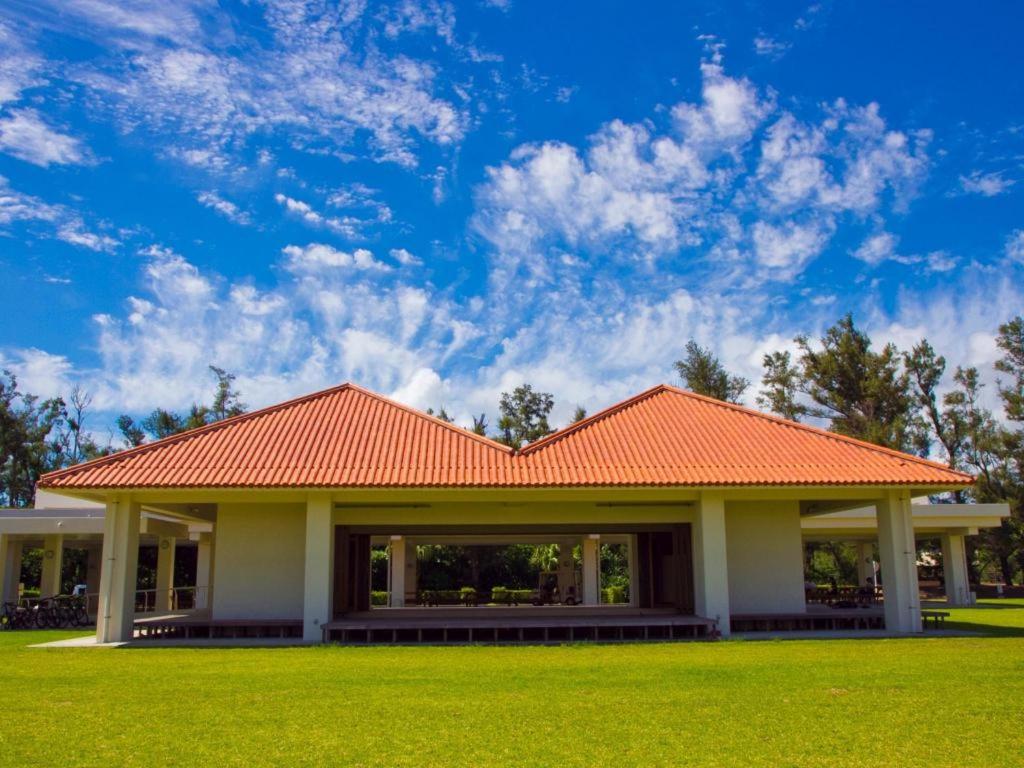 金武Nature Miraikan的绿色田野上一座带橙色屋顶的房子
