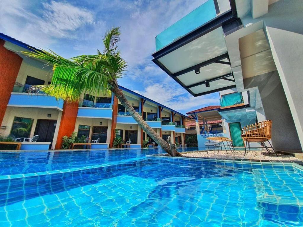 宋卡The Bed Vacation Rajamangala Hotel的一座游泳池,旁边是一座棕榈树