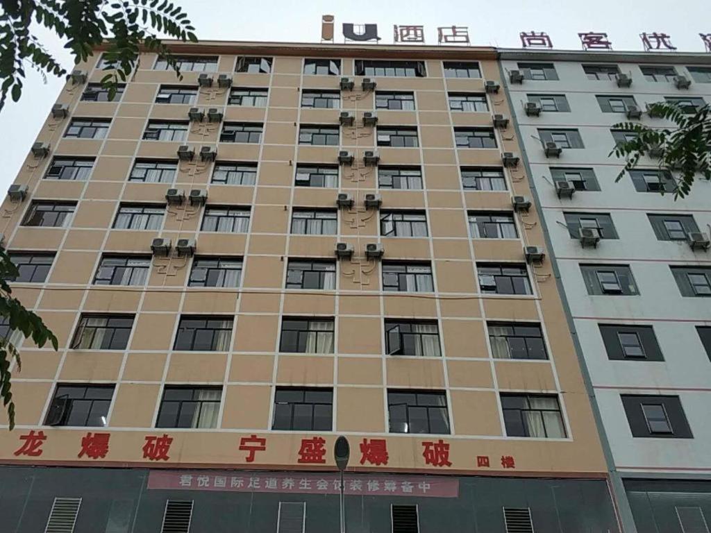 威宁IU Hotels·Bijie Weining Caohai Railway Station的一座高大的建筑,上面写着中国文字