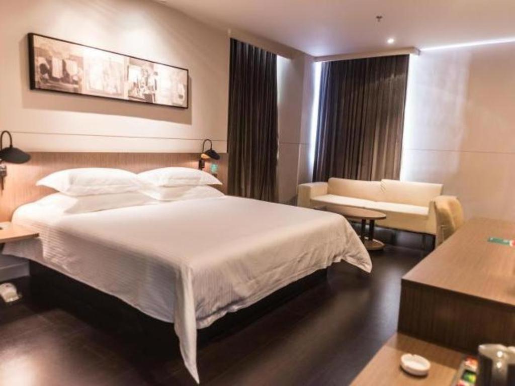 呼和浩特Jinjiang Inn Select Hohhot Chengjisihan Square Metro Station的卧室配有一张白色的大床和一张沙发。