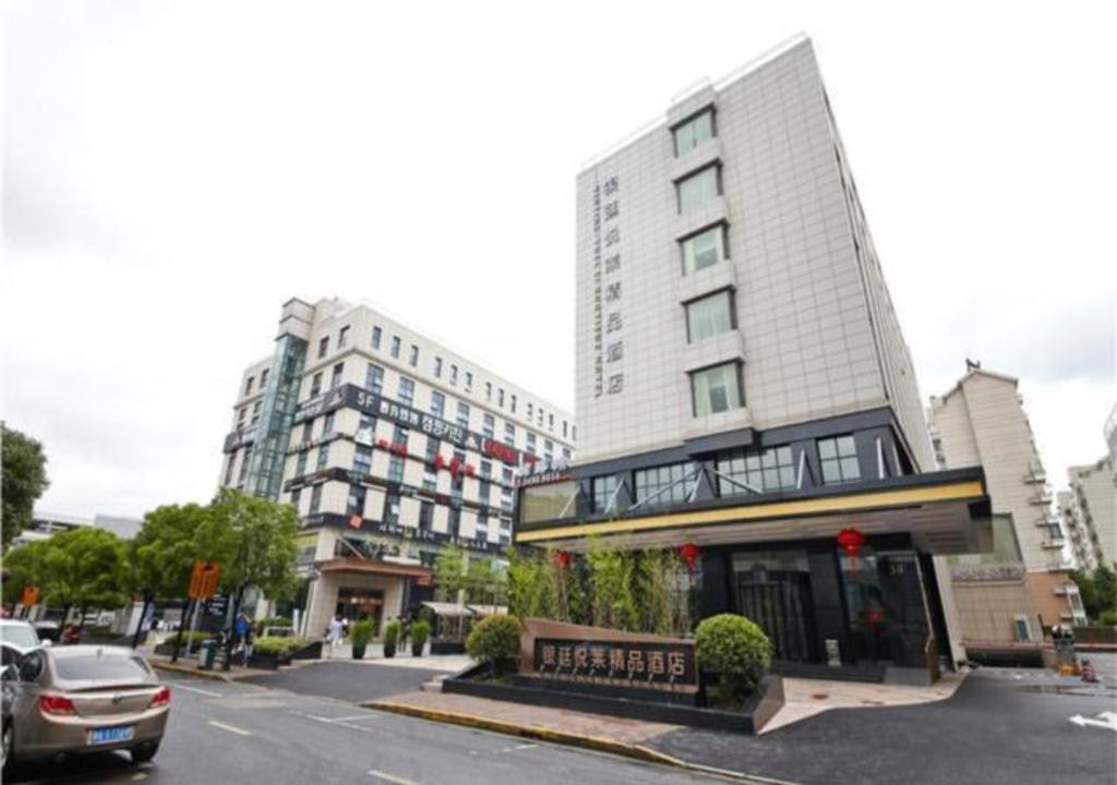 上海Echarm Plus Hotel Shanghai Hongqiao Korean Street Yinting Road的街道上的建筑物,前面有车辆停放