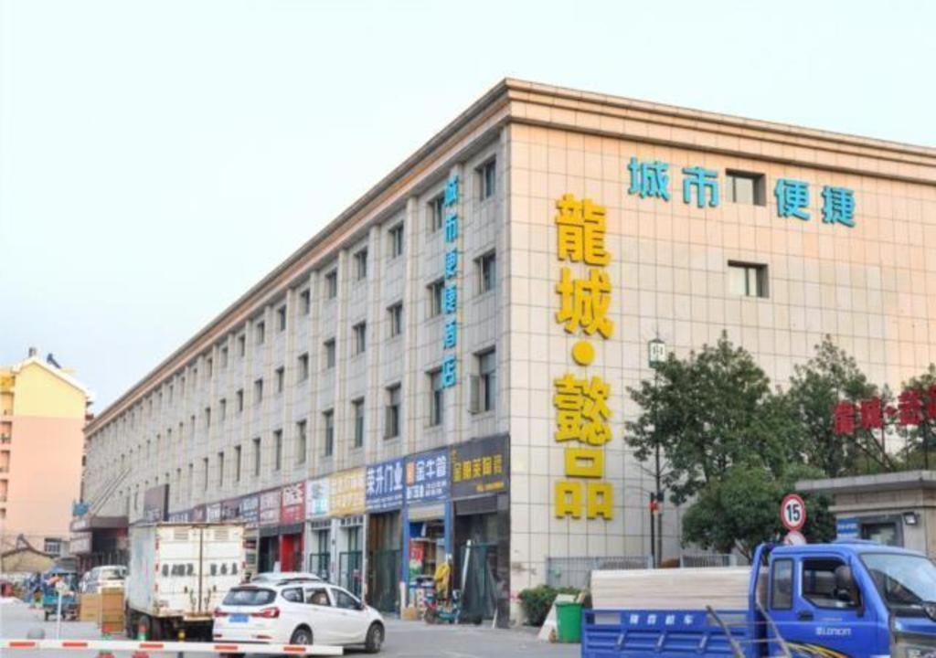 武汉City Comfort Inn Wuhan Tianhe Airport Julong Avenue Metro Station的一座大型建筑,前面有汽车停放