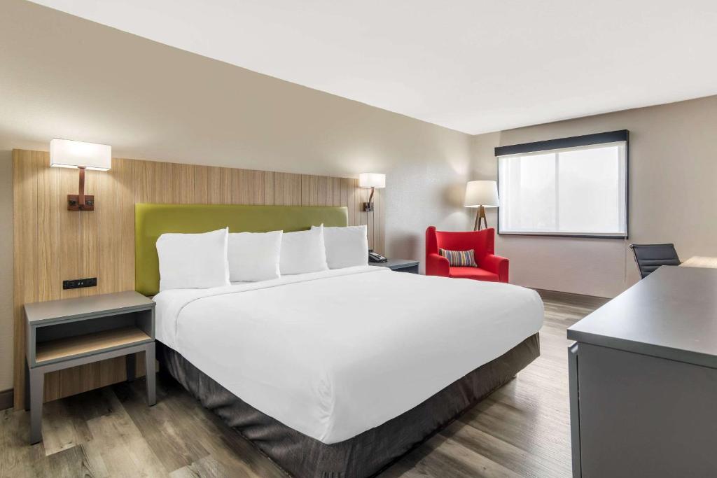 亚特兰大亚特兰大机场江山旅馆的一张大白色的床,位于一个红色椅子的房间