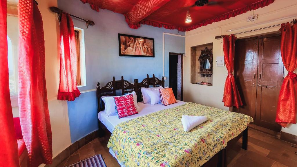 斋沙默尔萨加尔酒店的一间设有床铺的卧室,位于一间设有红色窗帘的房间