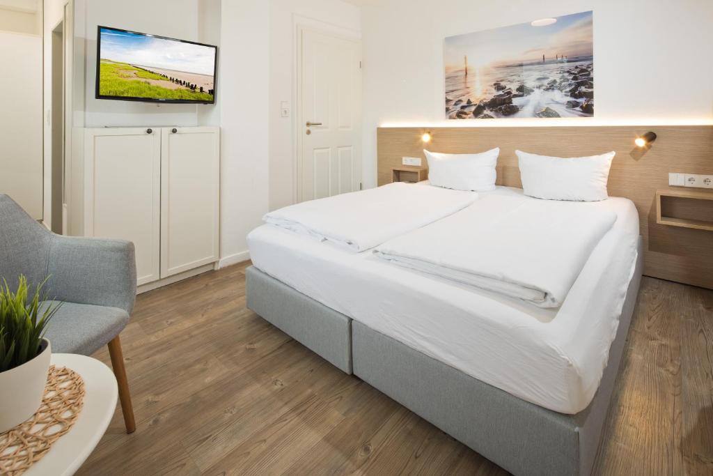 诺德奈Haus Menno Janssen - Doppelzimmer的卧室配有一张白色大床和电视。