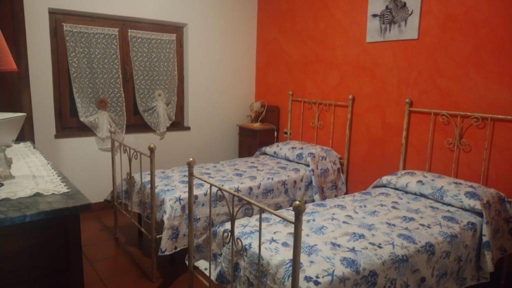 特乌拉达Casa vacanza Il Podere的橙色墙壁客房的两张床
