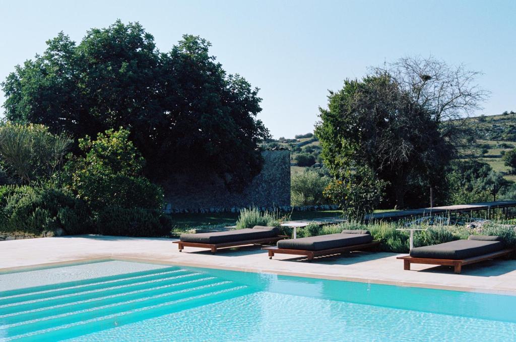 诺托Dimora delle Balze的游泳池旁设有2个长椅和1张桌子