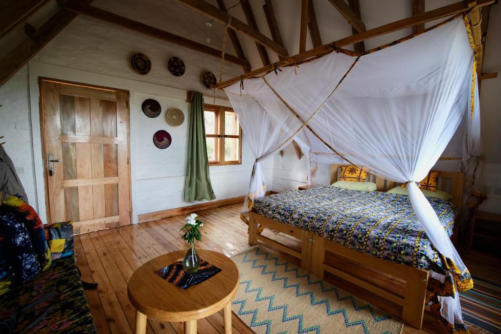 SangaHyena Hill Lodge的一间卧室配有一张天蓬床和一张桌子