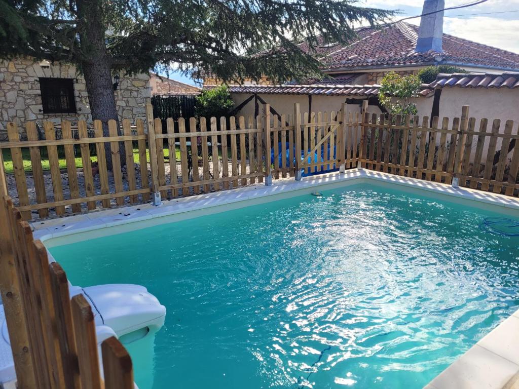佩德拉萨Casa Rural Pedraza的一个带木栅栏和蓝色海水的游泳池