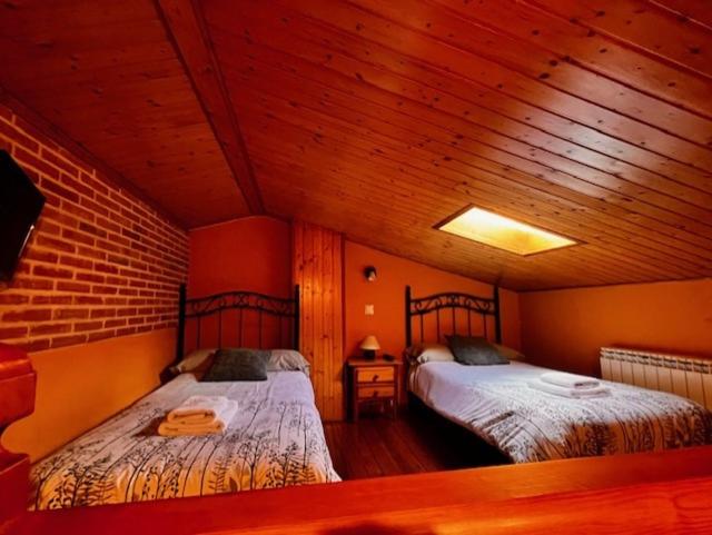 San Martín de la Vega del Alberchela cabaña de gredos的配有木天花板的客房设有两张床。