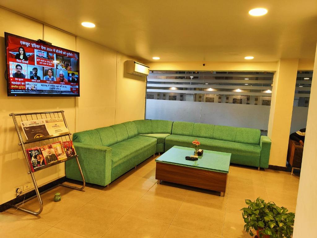新德里RoseMallow Tavisha Hotel的客厅配有绿色沙发和电视