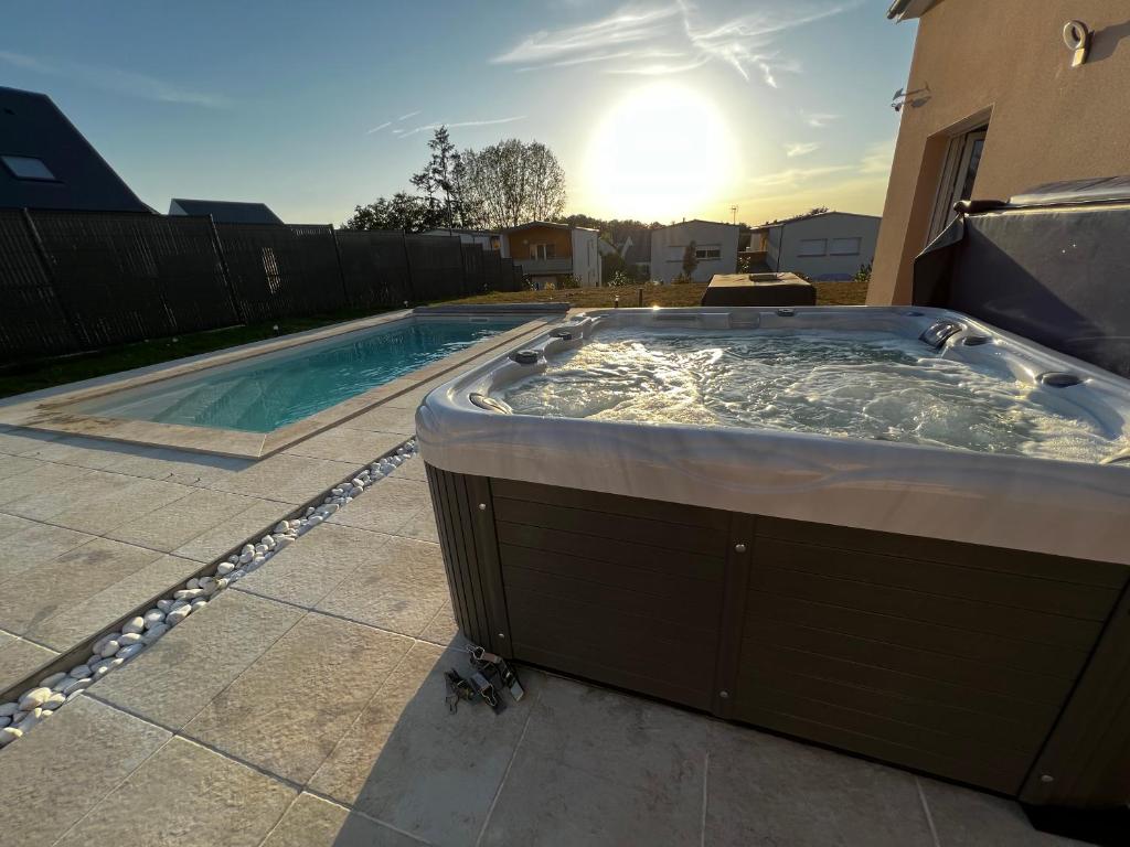 阿姆博斯Maison chaleureuse tout confort的后院的热水浴池,背面有阳光