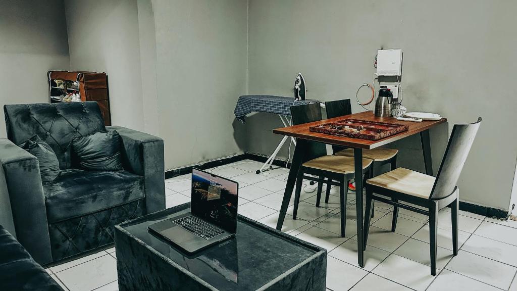 迪拜Dubai Zeus Hostel的客厅配有桌椅和笔记本电脑
