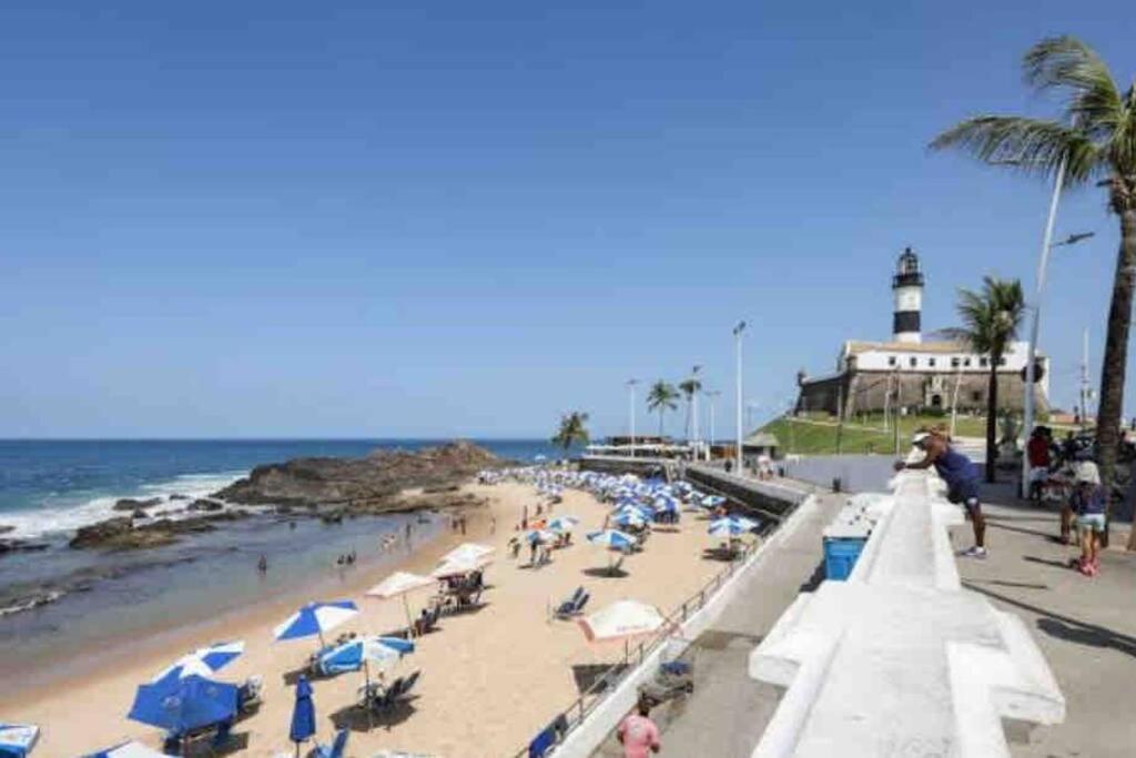 萨尔瓦多Vem curtir na praia e na cidade.的一片拥有众多人的海滩和一座灯塔