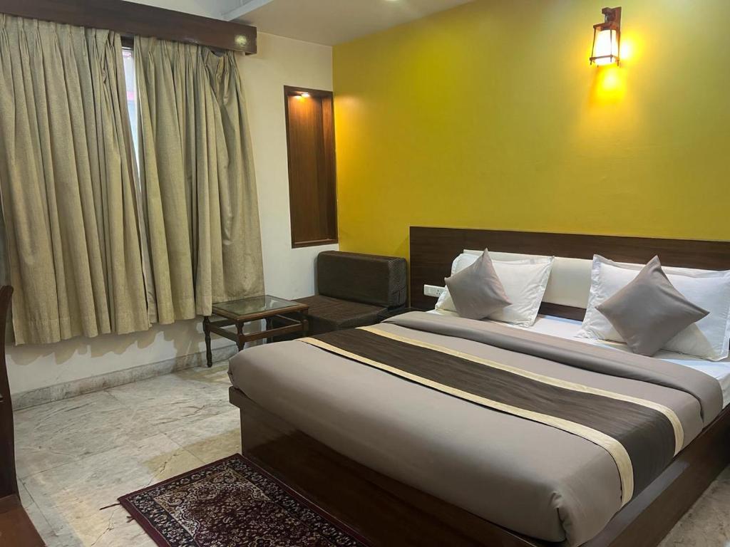 新德里Svaruchi Inn的一间卧室设有一张大床和黄色的墙壁