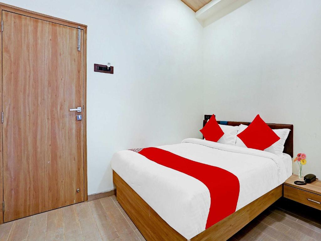 孟买Malali Residency的一间卧室配有一张带红色枕头的大床