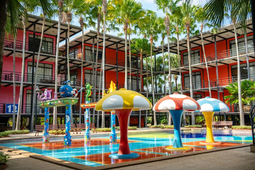 Ban Nong Chap TaoNongnooch Garden Pattaya Resort的一座带游泳池的大楼,位于度假村前