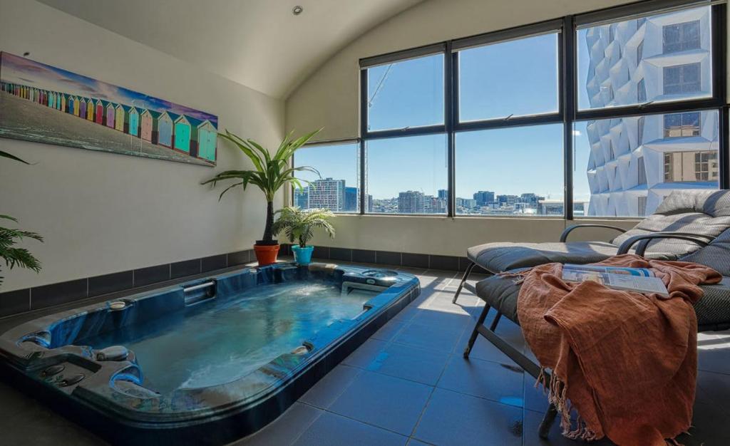 布里斯班Sleek Urban Oasis with Balcony的带沙发的房间内的大型室内热水浴池