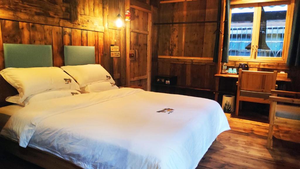 三江三江南夷民宿的卧室配有白色的木墙床
