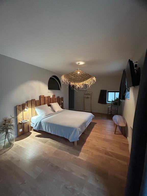 PersacChambres d'hôtes de la pilatière的一间卧室配有一张大床和一个吊灯。