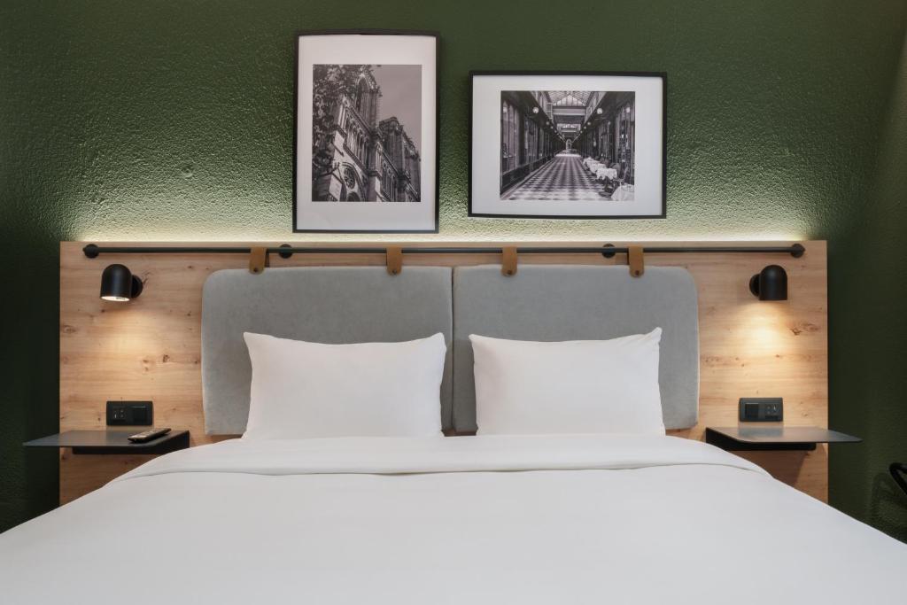 巴黎钟楼巴黎19维耶特酒店的卧室配有一张大床,墙上挂有三幅画
