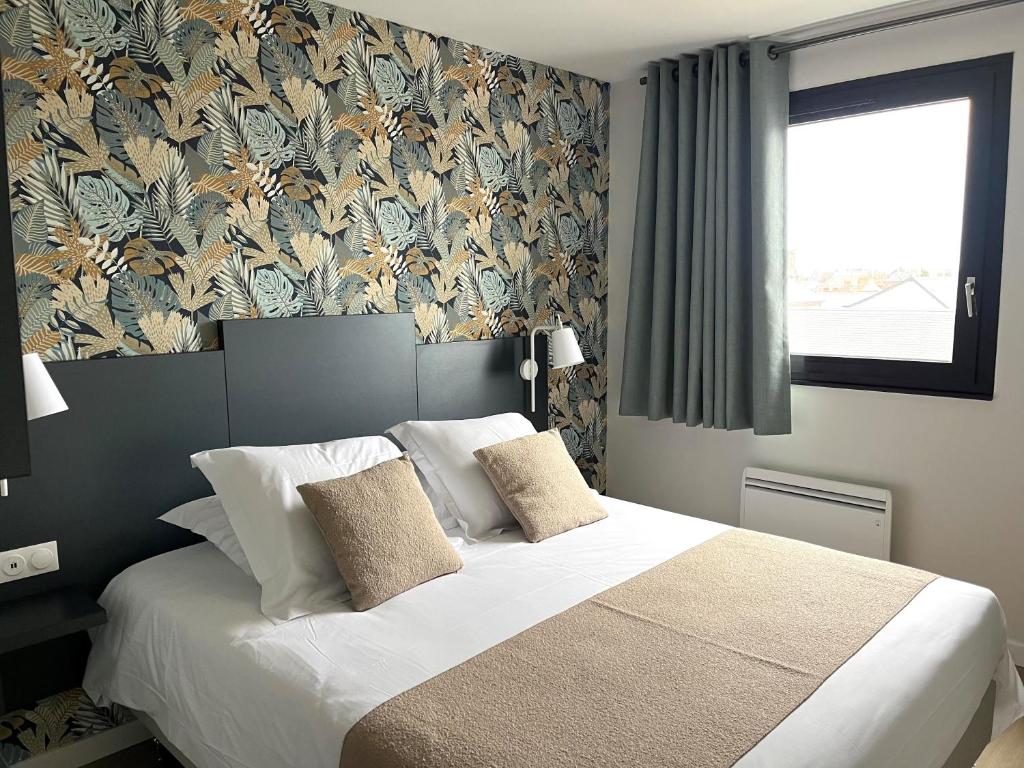 勒克罗图瓦Logis - Hôtel de la Baie de Somme的一间卧室配有一张带花卉壁纸的大床