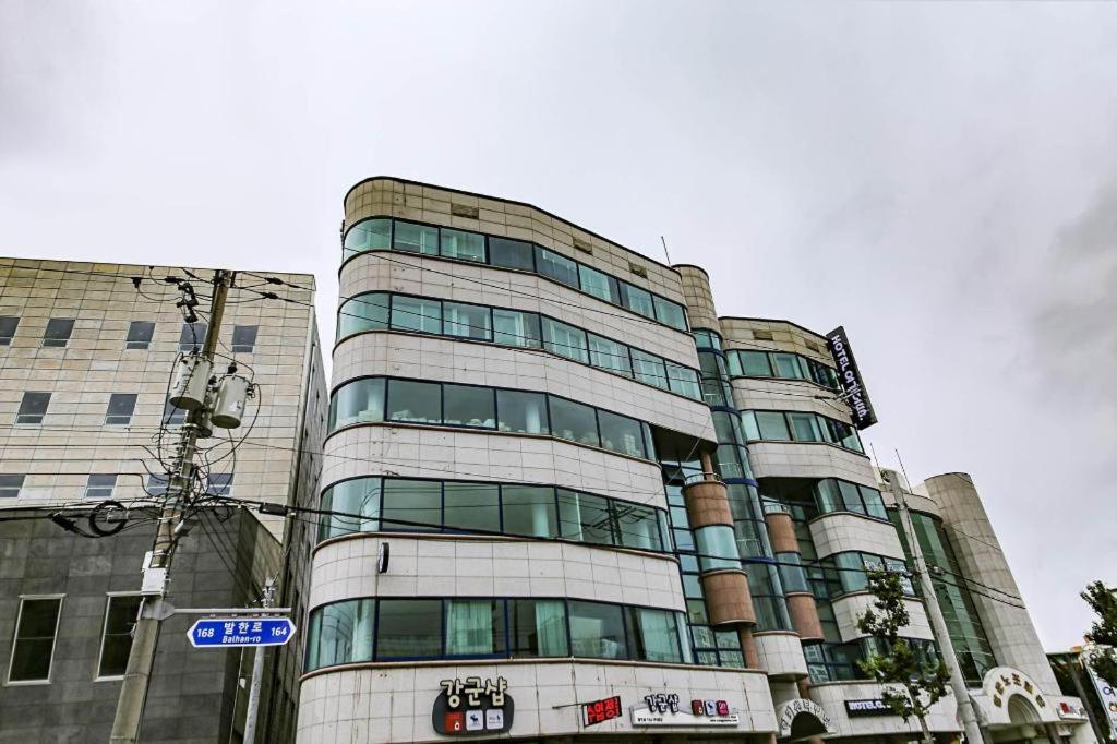 东海市Hotel Yeogiuhtte Donghae Mukho的一座高大的建筑,设有玻璃窗和街道标志