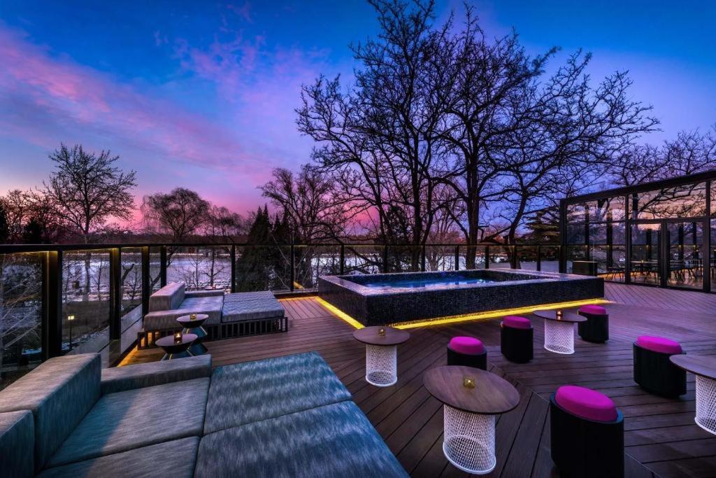 北京Blossom House Beijing Houhai的一个带游泳池、桌子和长凳的屋顶露台