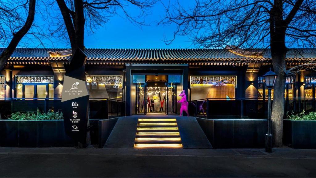 北京Blossom House Beijing Houhai的一位女士在晚上走上楼梯到一座建筑物