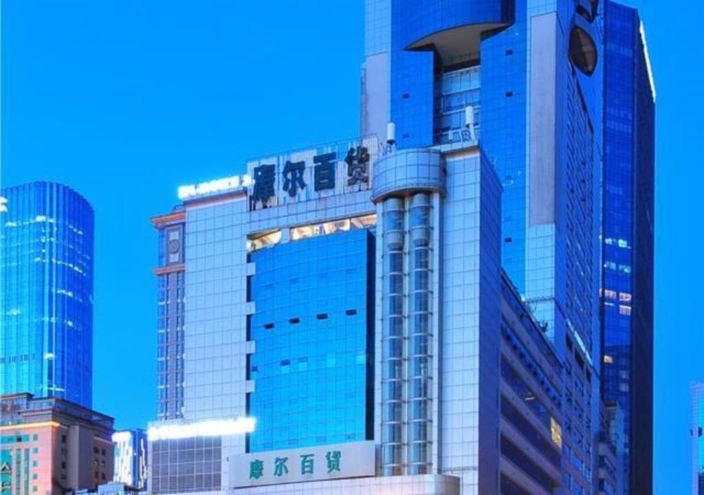 成都Borrman Hotel Chengdu Chunxi Road Tianfu Square Metro Station的一座高大的建筑,有蓝色的窗户,位于城市