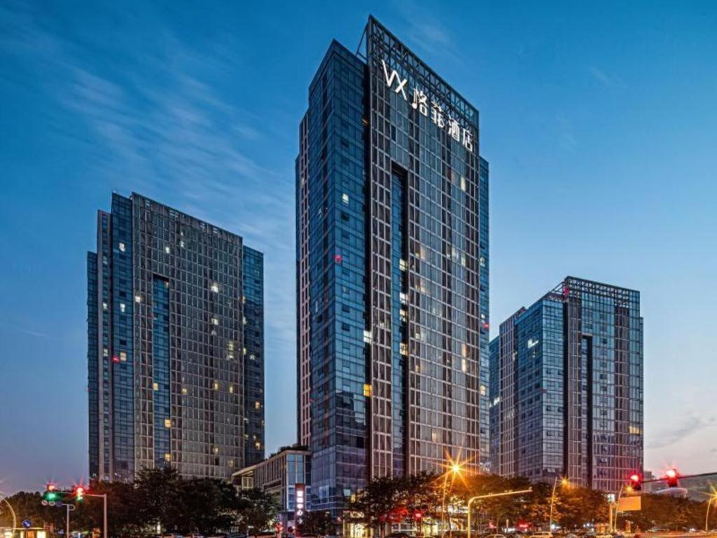 新安VX Hotel Wuxi Xinwu District Executive Center Wanda Plaza的夜城里两座高耸的摩天大楼