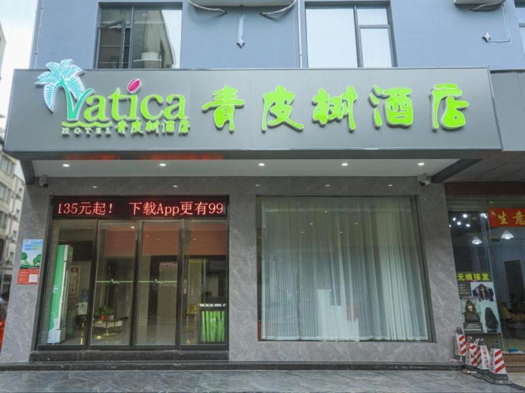 海口Vatica Hotel Haikou Jinniuling Park Haizhiyuan的建筑物一侧有标志的商店