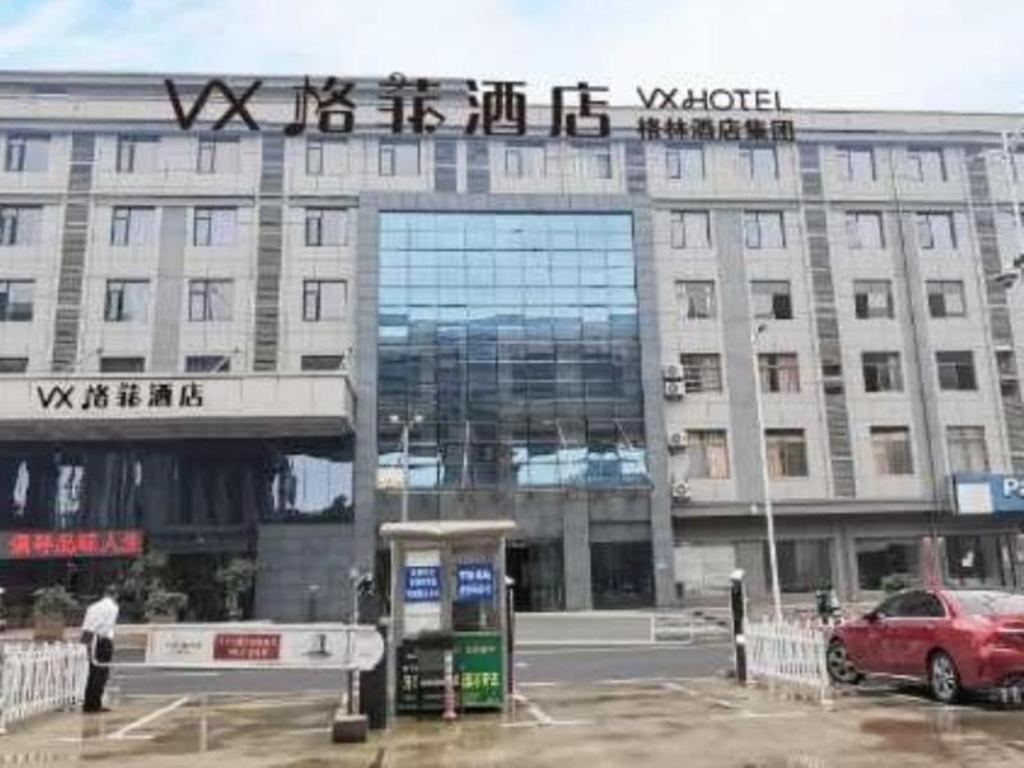 上饶VX Hotel Shangrao High-Speed Railway Station的前面有停车位的建筑