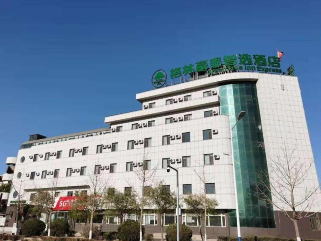 丹东GreenTree Inn Express Liaoning Jinzhou Bijia Mountain的白色的建筑,上面有标志
