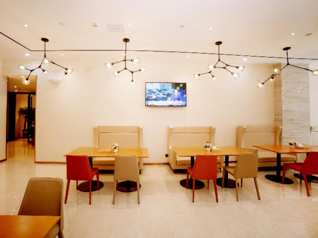 黄石City Comfort Inn Ezhou Huahu Airport High-speed Railway Station的一间带桌椅的餐厅以及墙上的电视