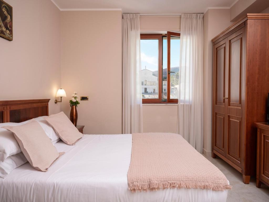 圣乔瓦尼·罗通多Hotel SAN PIO的卧室配有白色的床和窗户。