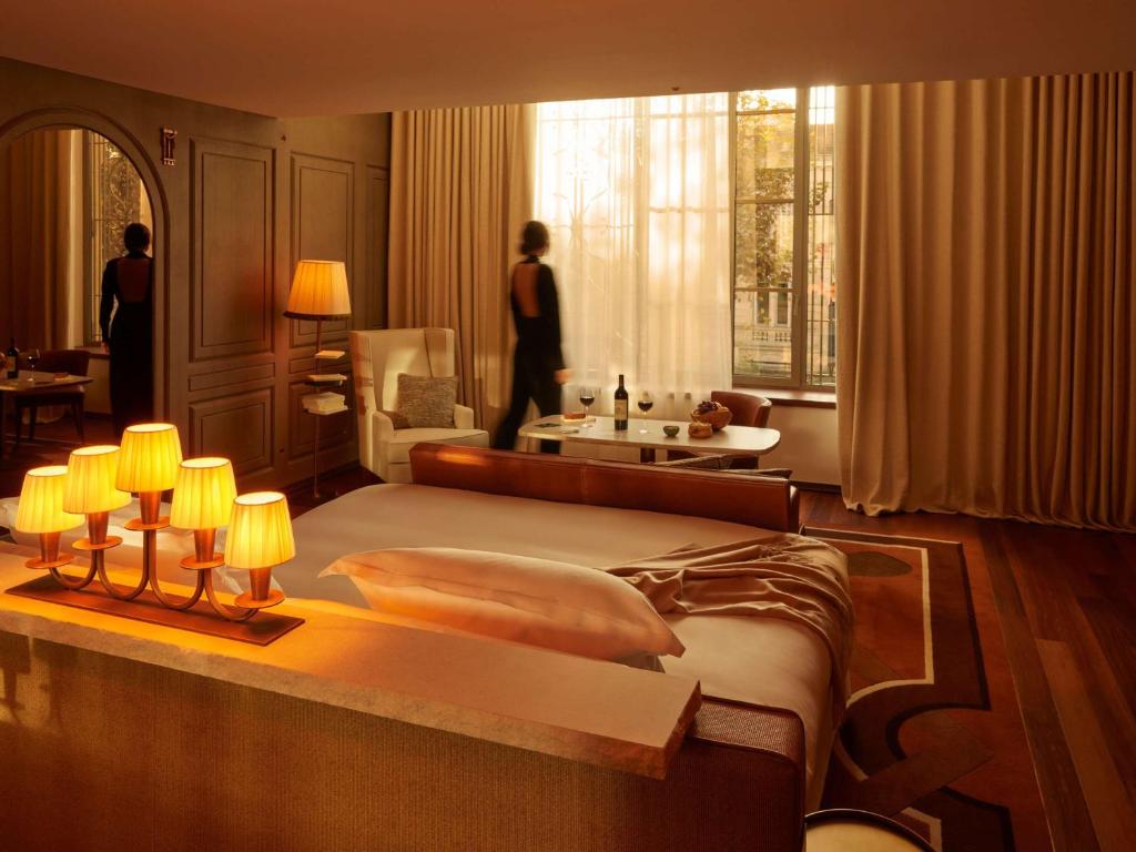 波尔多Mondrian Bordeaux Les Carmes的卧室配有一张大床,窗户上有一个女人